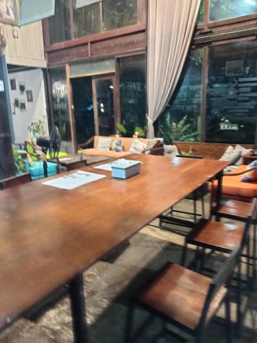 a large wooden table in a living room with chairs at Laanrablom Bed&Breakfast in Sara Buri