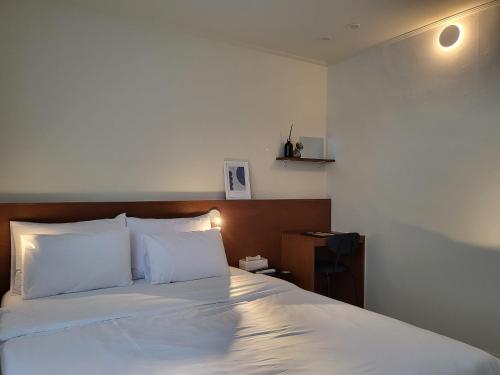 a bedroom with a bed with white sheets and a wooden headboard at jeonju hotel book and type in Jeonju
