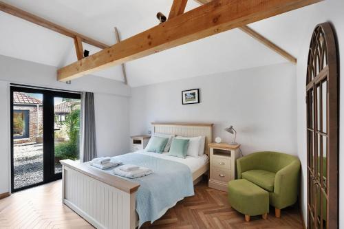 a bedroom with a bed and a green chair at Seven Space - Willow Barn, Hot Tub & Scenic Rural Retreat in Haddiscoe