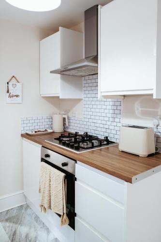 a kitchen with white cabinets and a stove at Osbourne House in Gillingham