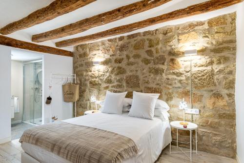 a bedroom with a bed and a stone wall at La Casa Del Miracle in Balaguer