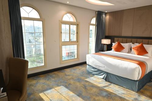 a bedroom with a large bed and windows at فندق امان أبها - المعالي in Abha