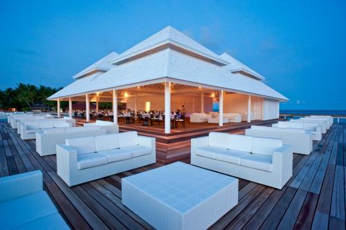 a pavilion on the beach with white couches and tables at Diamonds Thudufushi Maldives Resort & Spa in Thundufushi