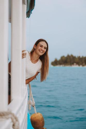 a woman standing on the side of a boat at Diamonds Thudufushi Maldives Resort & Spa in Thundufushi