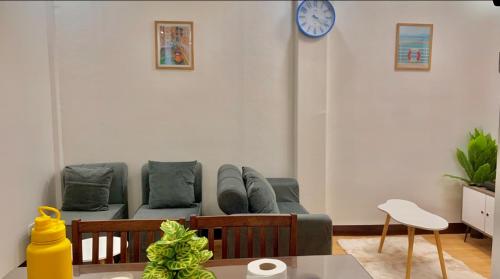 a living room with a couch and a clock on the wall at MAYABO CONDO by Urban Deca Home Batangas in Batangas City