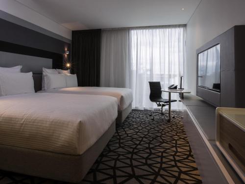 a hotel room with two beds and a television at Pullman Sydney Airport in Sydney