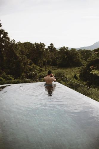 a man is sitting in a pool of water at Serene Vita Retreat in Phumĭ Ŏng Char