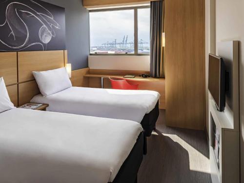 a hotel room with two beds and a television at ibis Santos Valongo in Santos