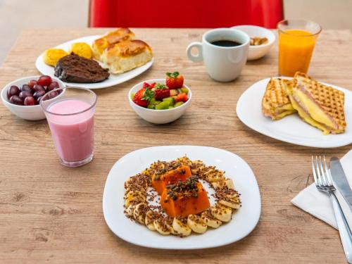 a table with plates of breakfast foods and drinks at ibis Santos Valongo in Santos
