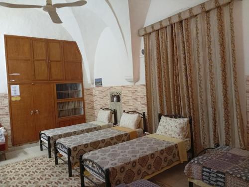 a room with three beds and a chair and a window at Soufan Guest HOUSE in Nablus