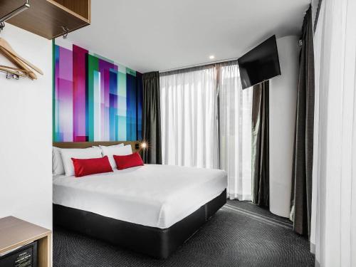 a bedroom with a large bed with a colorful wall at ibis Styles Brisbane Elizabeth Street in Brisbane