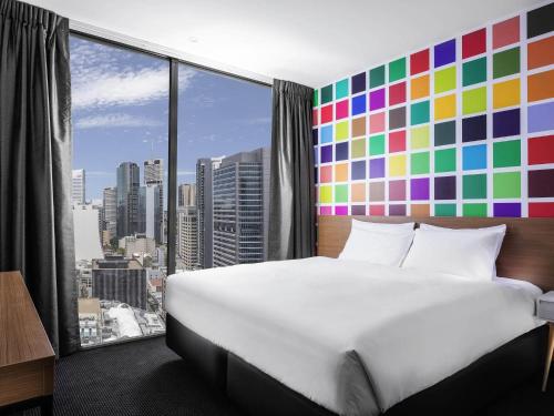 a bedroom with a large bed and a large window at ibis Styles Brisbane Elizabeth Street in Brisbane