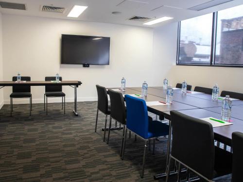 a conference room with tables and chairs and a screen at ibis Styles Brisbane Elizabeth Street in Brisbane