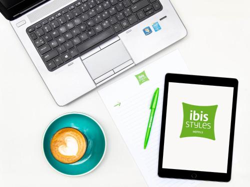 a desk with a laptop and a tablet and a cup of coffee at ibis Styles Brisbane Elizabeth Street in Brisbane