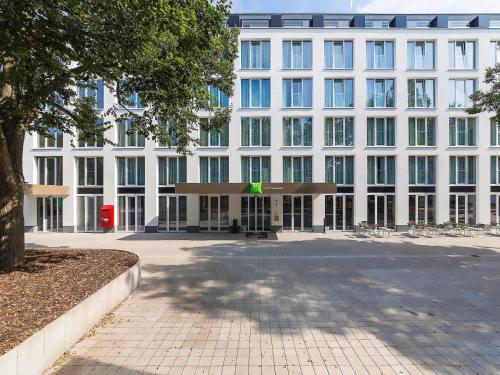 a large white building with a green sign in front at ibis Styles Rastatt Baden-Baden in Rastatt