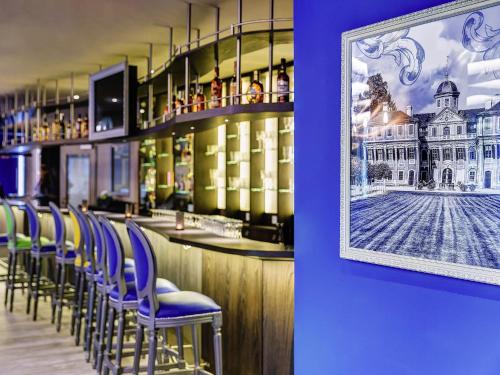 a bar with blue chairs and a picture of a building at ibis Styles Rastatt Baden-Baden in Rastatt