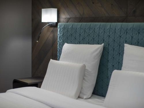 a bed with a blue headboard and two pillows at Pullman Riga Old Town in Rīga