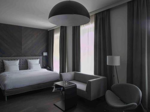 a bedroom with a bed and a couch and a chair at Pullman Riga Old Town in Rīga