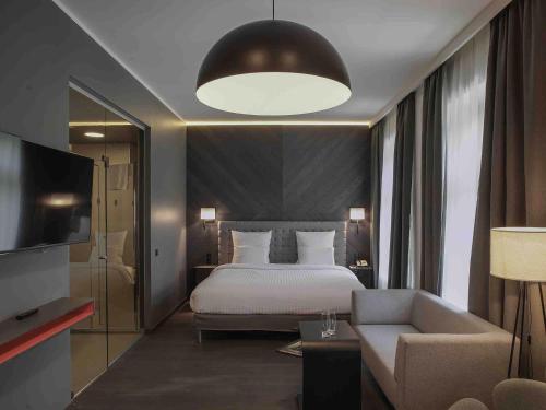 a bedroom with a bed and a couch and a television at Pullman Riga Old Town in Rīga