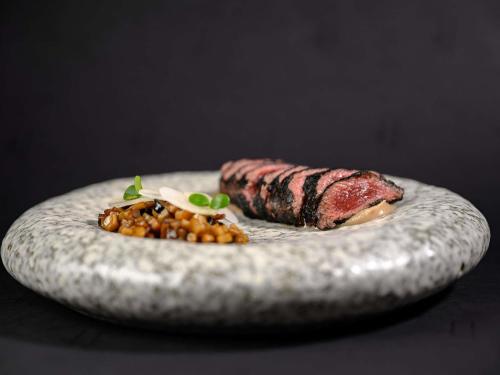 a plate of food with a steak and beans at Pullman Riga Old Town in Rīga
