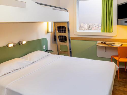 a bedroom with a large bed and a window at ibis budget SP Frei Caneca in Sao Paulo