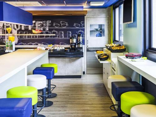 a kitchen with green and blue stools in a restaurant at ibis budget SP Frei Caneca in Sao Paulo