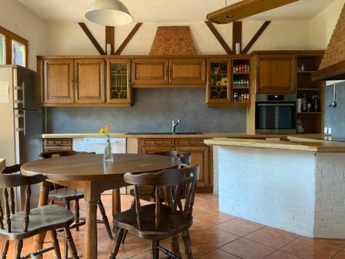 a kitchen with a wooden table and chairs and a counter at Cozy family home in Champagne-en-Ardenne 8p in Rubigny