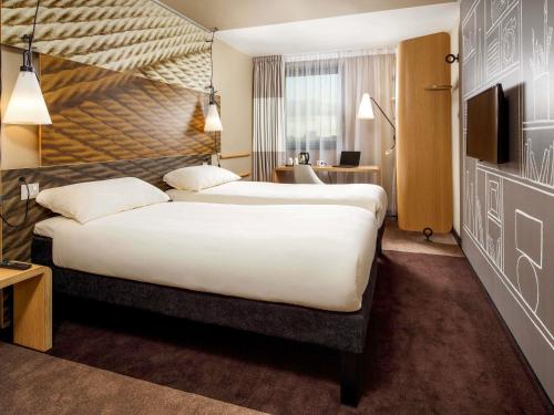 a hotel room with a large bed and a desk at ibis Cambridge Central Station in Cambridge