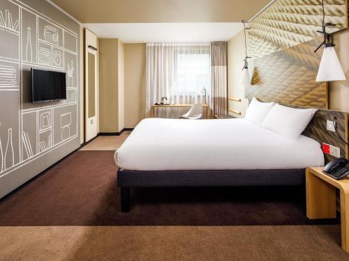 a hotel room with a large bed and a television at ibis Cambridge Central Station in Cambridge