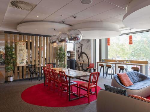 a dining room with a table and red chairs at ibis Cambridge Central Station in Cambridge