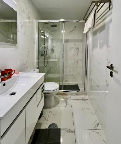 a white bathroom with a shower and a toilet at Almada Downtown 201 in Porto