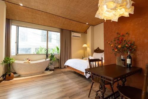 a bedroom with a tub and a bed and a table at PINhome in Ho Chi Minh City