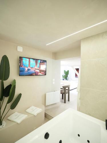 a white bathroom with a tub and a tv on the wall at crystal stay in Melun