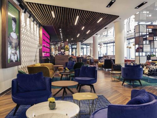 a lobby with blue chairs and tables in a building at Mercure Krakow Stare Miasto in Kraków