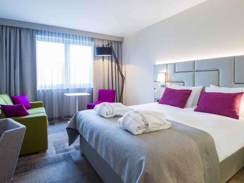 a hotel room with a large bed and purple chairs at Mercure Krakow Stare Miasto in Kraków