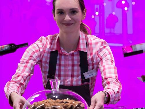 a woman in an apron holding a bowl of food at Mercure Krakow Stare Miasto in Kraków