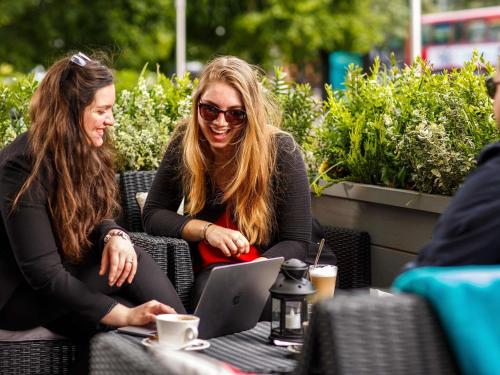 two women sitting at a table with a laptop at ibis Styles London Ealing in London
