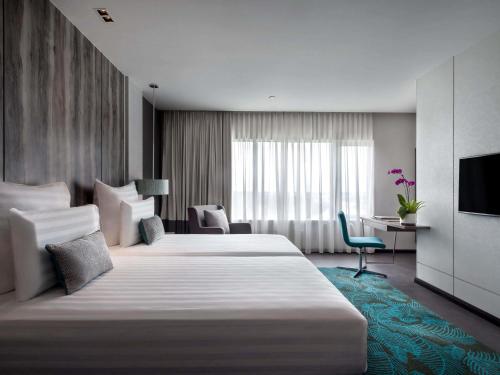 a hotel room with two beds and a television at Pullman Miri Waterfront in Miri