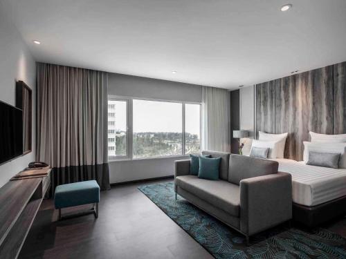 a hotel room with a bed and a couch at Pullman Miri Waterfront in Miri