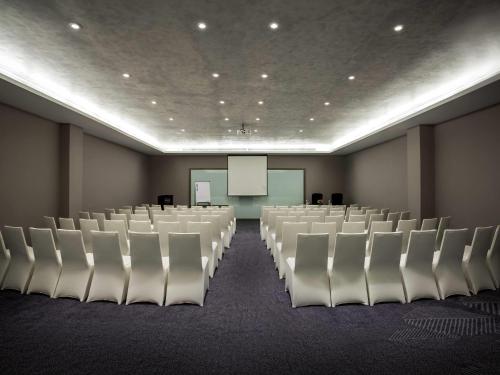 a conference room with white chairs and a screen at Pullman Miri Waterfront in Miri