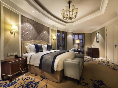 a bedroom with a large bed and a chandelier at Pullman Tangshan in Tangshan