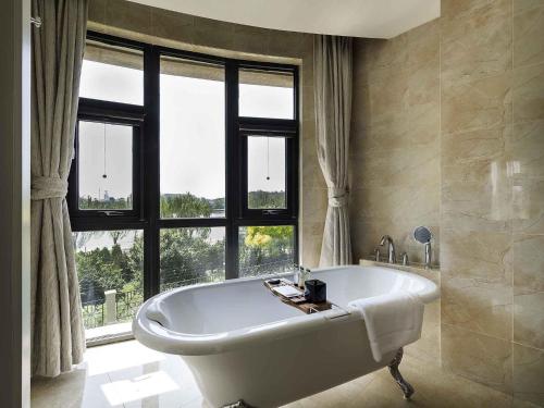 a large bathroom with a tub in front of a window at Pullman Tangshan in Tangshan