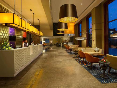 a restaurant with tables and chairs in a building at Grand Mercure Mysore - An Accor Brand in Mysore