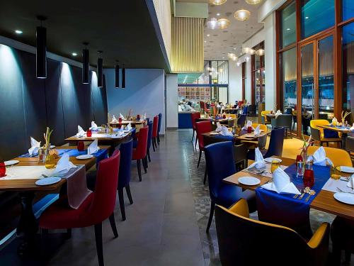 a restaurant with wooden tables and chairs and tablesktop at Grand Mercure Mysore - An Accor Brand in Mysore