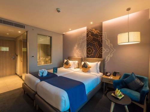 a hotel room with a large bed and a chair at Grand Mercure Mysore - An Accor Brand in Mysore
