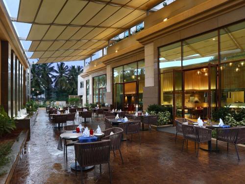 a restaurant with tables and chairs in a building at Grand Mercure Mysore - An Accor Brand in Mysore