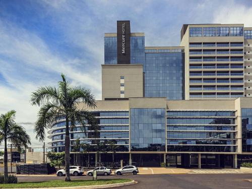 a large building with cars parked in a parking lot at Mercure Ribeirao Preto in Ribeirão Preto