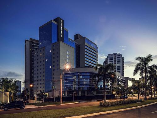 a large blue building with palm trees in front of it at Mercure Ribeirao Preto in Ribeirão Preto