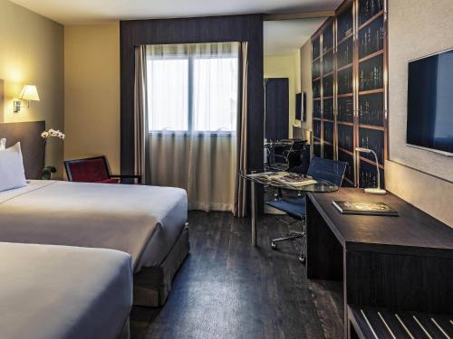a hotel room with two beds and a desk with a computer at Mercure Ribeirao Preto in Ribeirão Preto