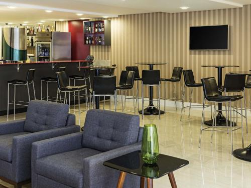 a lobby with chairs and a bar with a tv at Mercure Ribeirao Preto in Ribeirão Preto